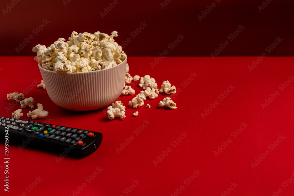 Bowl with popcorn, TV remote and space for text on color background, top view. Watching movie