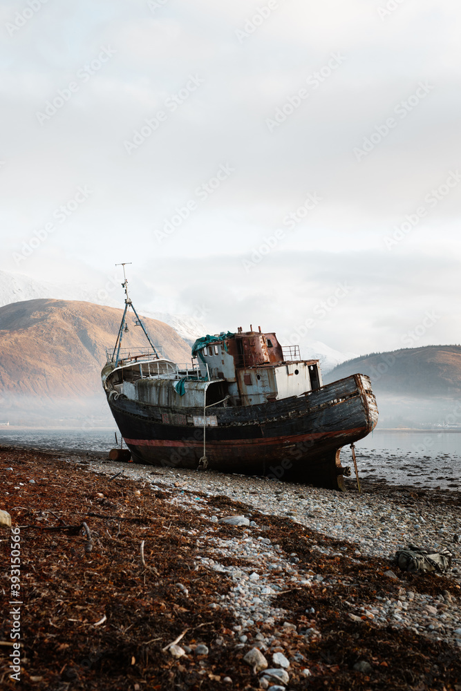 Old rusty fishing boat moored on beach in foggy morning in Scottish Highlands Old rusty fishing boat moored on beach in foggy morning in Scottish Highlands