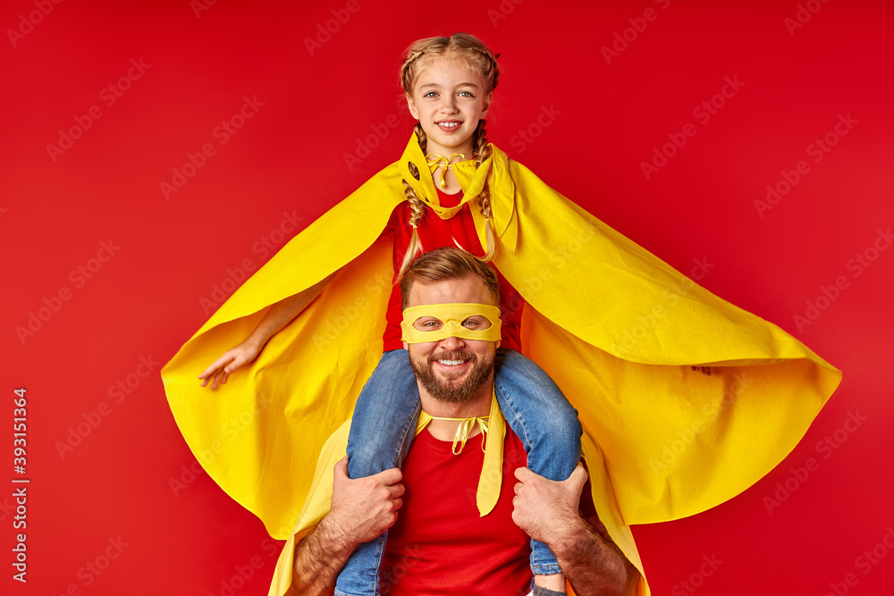 flying child girl on shoulders of super father isolated over red background, in yellow cloaks