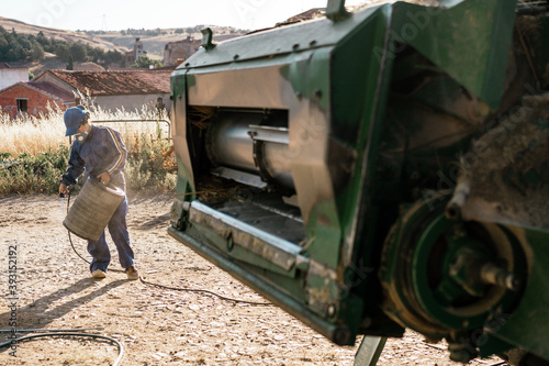 Unrecognizable farmer in workwear cleaning filter of agricultural combine harvester in farm yard