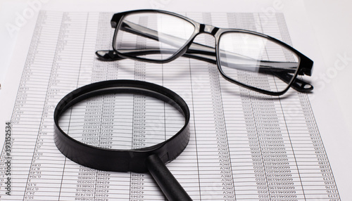 Black rimmed glasses and a magnifying glass lie on the reports
