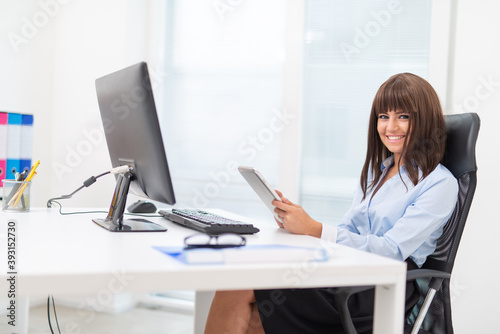 Woman using her tablet in front of her desktop computer