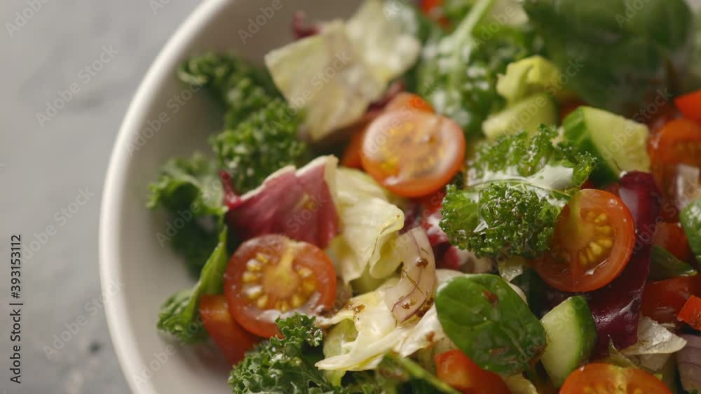 A juicy healthy vegetable salad is dressed with olive oil, the camera moves to the salad. Cucumbers, tomatoes, lettuce, iceberg lettuce. close-up A juicy healthy vegetable salad is dressed with olive oil, the camera moves to the salad. Cucumbers, tomatoes, lettuce, iceberg lettuce. close-up