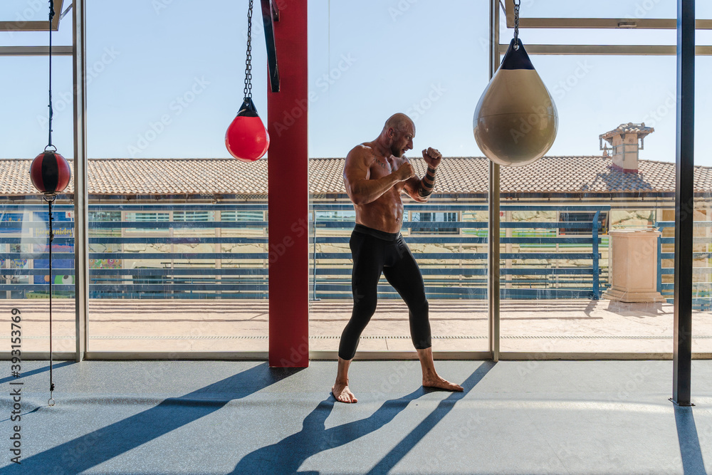 Foto de Side view of determined male boxer in boxing gloves punching ...