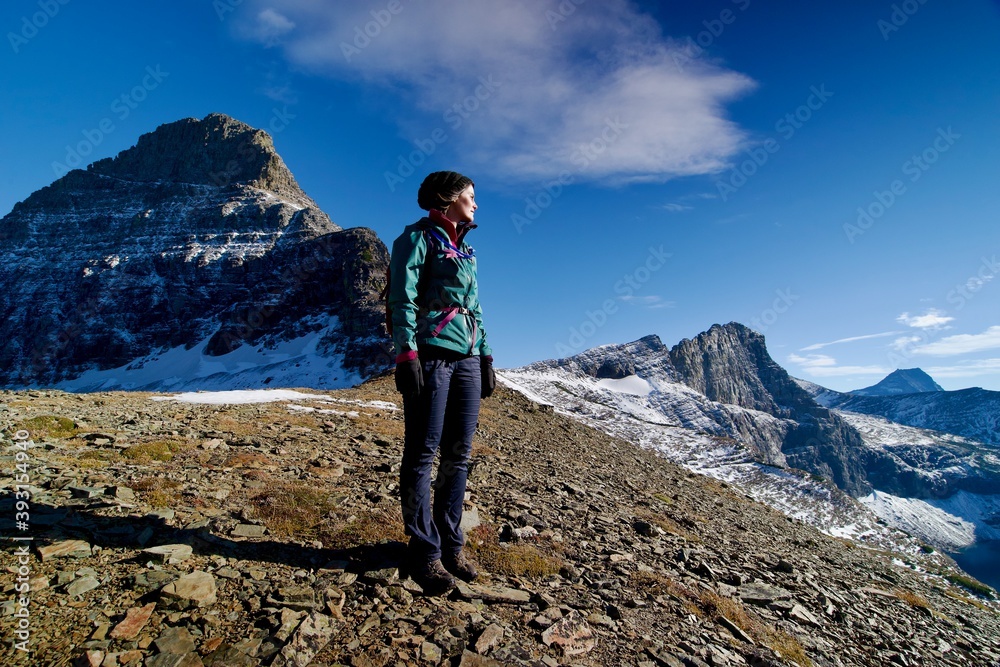 Fototapeta premium Young woman on top of dramatic mountaintop looking into distance