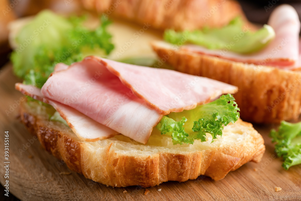 Croissant with ham and cheese on wooden background, closeup view