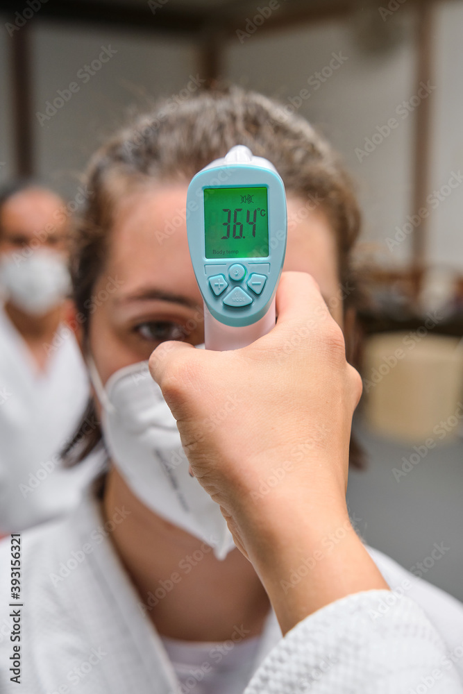 Temperature test machine in front of a row of people wearing a kimono and mask in a krav maga gym Temperature test machine in front of a row of people wearing a kimono and mask in a krav maga gym