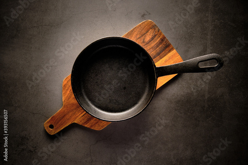 Top view of metal frying pan placed on wooden cutting board on table in kitchen