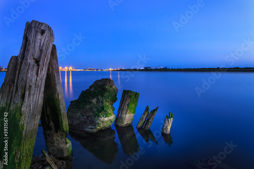 remains of a jetty in the water with the city on the horizon at night