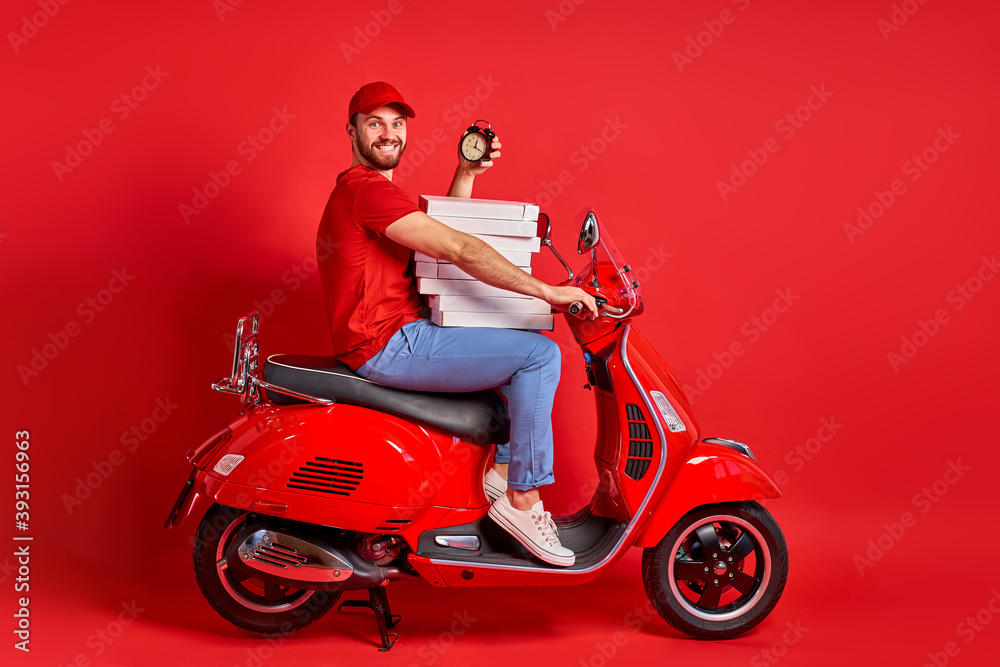 studio shoot of young delivery man of takeaway on scooter with food case  box driving fast, express food delivery service from cafes and restaurants.  caucasian courier on the moto scooter isolated foto