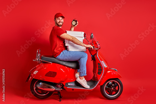 studio shoot of young delivery man of takeaway on scooter with food case box driving fast  express food delivery service from cafes and restaurants. caucasian courier on the moto scooter isolated