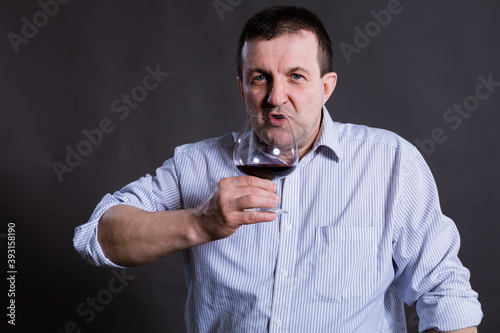 Middle aged cheerful man dressed in a shirt with glass of wine