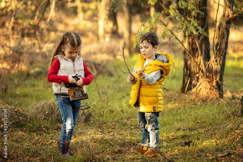 cute boy and girl 4 years old play with an old film camera and take pictures of each other