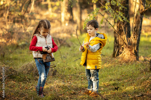 cute boy and girl 4 years old play with an old film camera and take pictures of each other