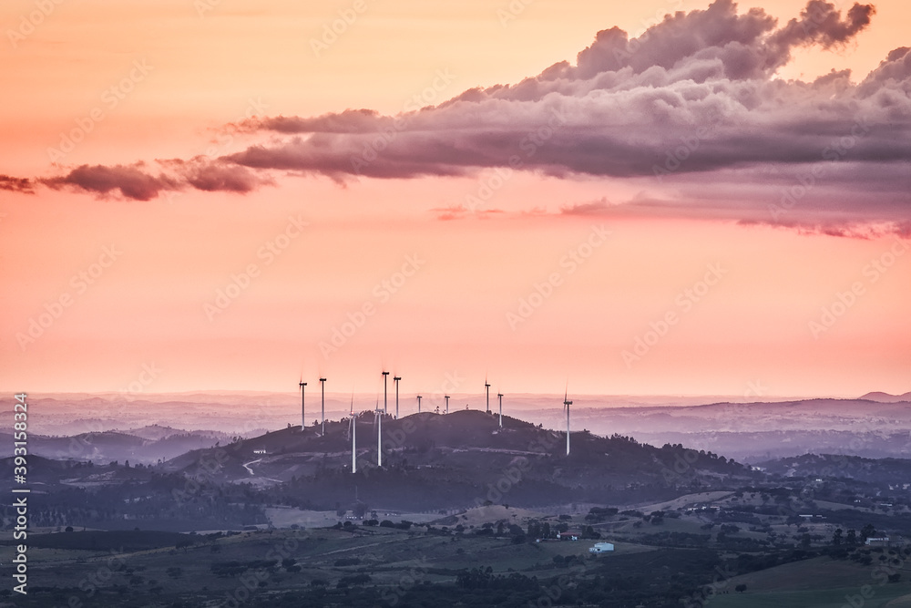 Windmills on a hill with fog on the horizon and clouds in the sky Windmills on a hill with fog on the horizon and clouds in the sky