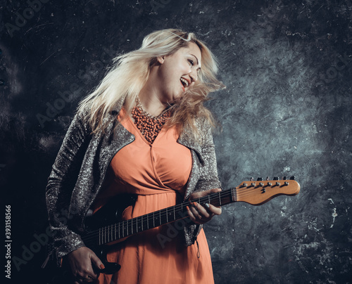 Attractive plump rocker woman with electric guitar