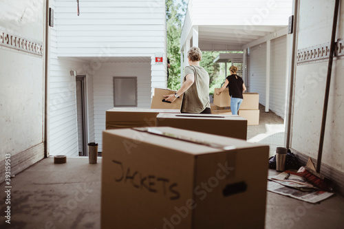 Female friends carrying cardboard boxes during relocation photo