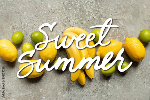 top view of colorful bananas, limes and lemons on grey concrete surface, sweet summer illustration