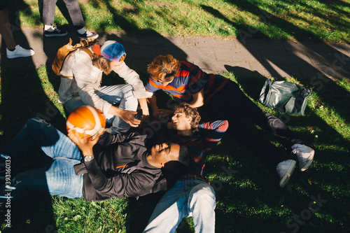 High angle view of smiling male friends sitting in park