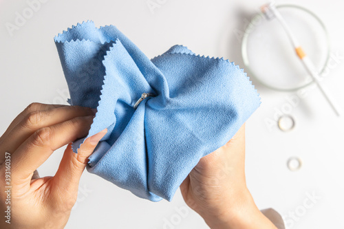 Fotografie Woman hands cleaning and polishing golden jewelry at home