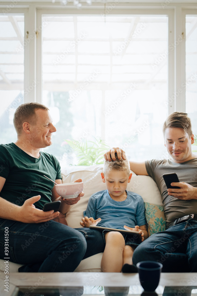Smiling fathers talking while son using digital tablet at home Smiling fathers talking while son using digital tablet at home