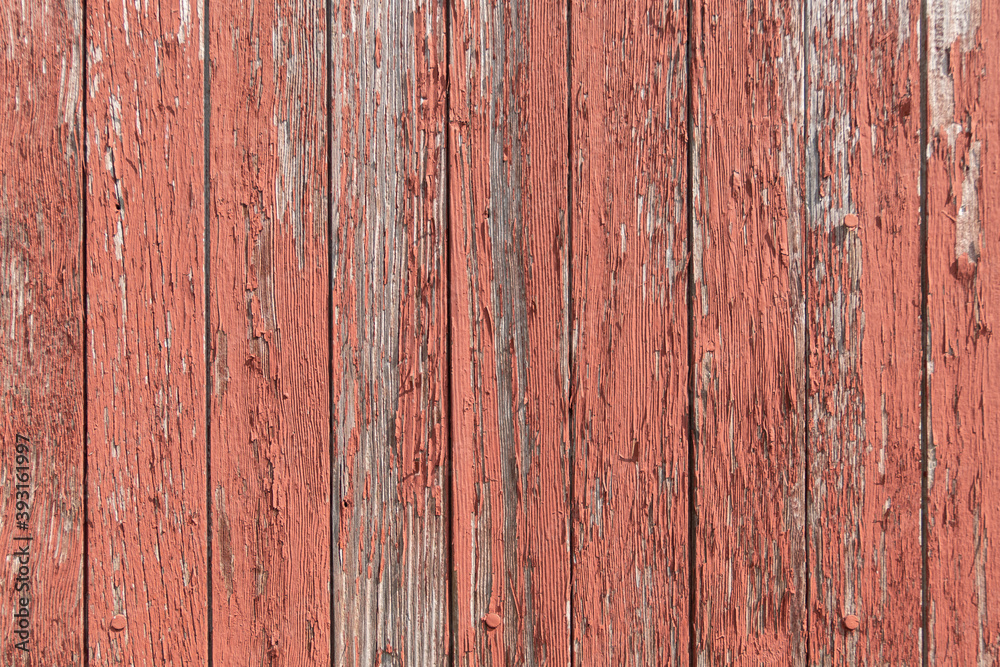 Red paint peeling off of old wooden boards on the side of a barn texture