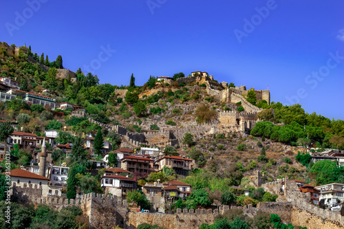 Old town in Alanya (Turkey). Ancient ruins of fortress walls and modern cottages on the hillside. Tourist cityscape of the Turkish resort city
