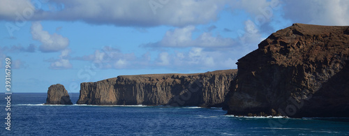 Panoramic image of rocky coast with cliffs, calm sea and blue sky with clouds, north of Gran Canaria, Spain