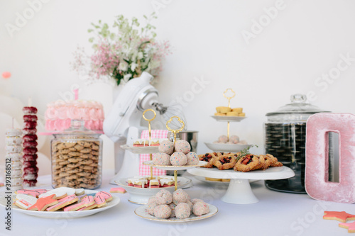 Dessert spread at girl's birthday party with cookies, cake with pink frosting and flowers