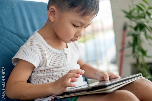 Little Asian Kid's using Digital Touchscreen Phone Tablet Computer Playing Games.