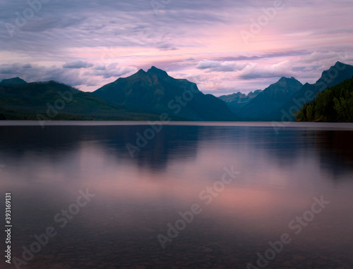 A bright summer sunset at Lake McDonald in Glacier National Park, Montana. Mountains reflecting in a lake. 