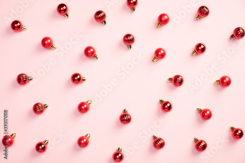 Red Christmas balls decoration on pastel pink background. Creative flat lay style composition, top view. Minimal style. Christmas, New Year, winter holiday poster, greeting card mockup.