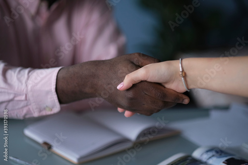 African American businessman shaking hands with caucasian businesswoman. Close up of African American man shaking hand with his his female colleague in office. Concept of meeting