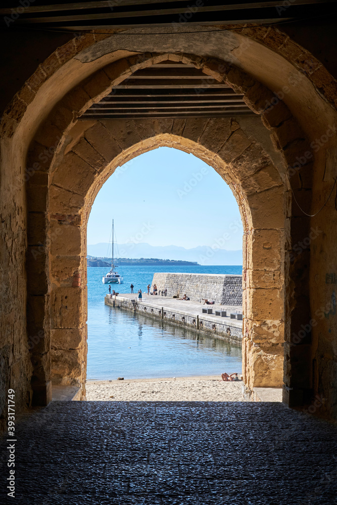 view through a medieval arch towards the sea in front of cefalu