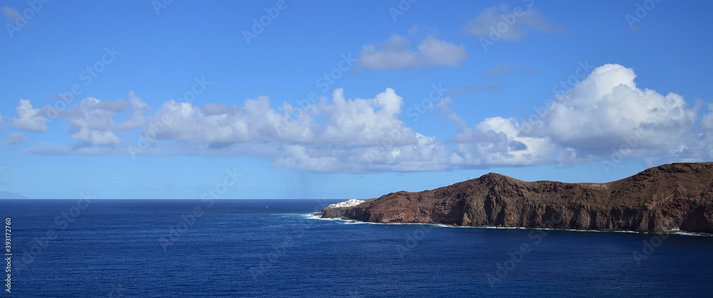 Panoramic image with calm sea, intense blue sky and low clouds, coast of Sardina, Galdar, Gran Canaria Panoramic image with calm sea, intense blue sky and low clouds, coast of Sardina, Galdar, Gran Canaria
