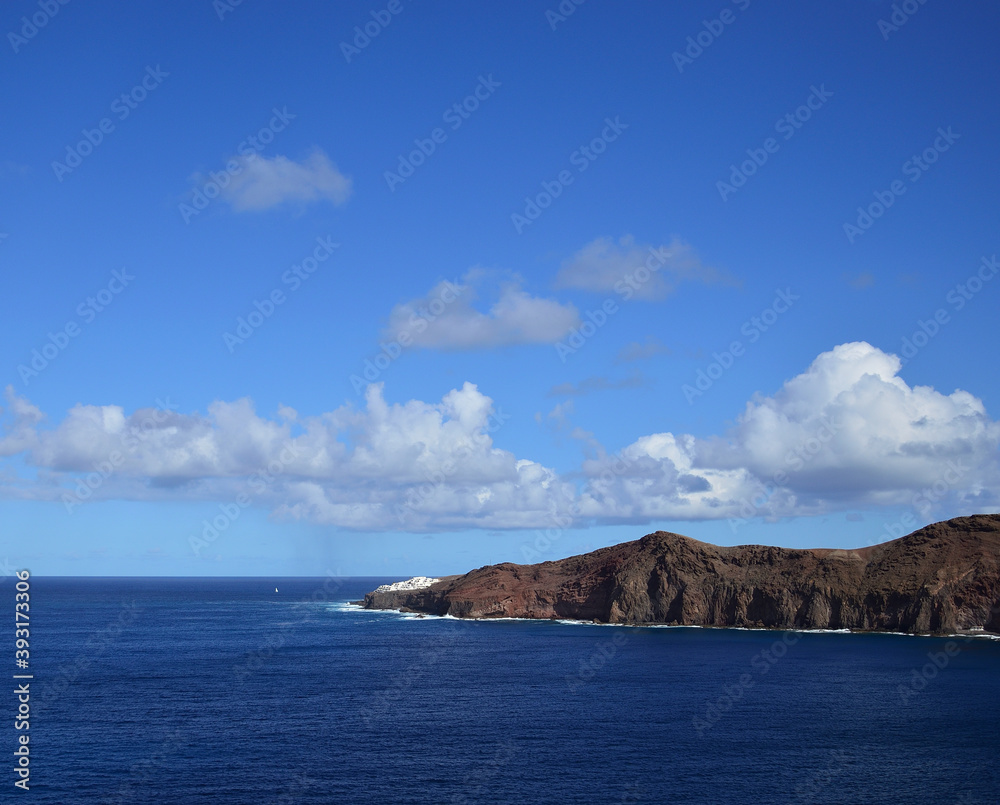 Splendid coastal image with intense blue sky, low clouds and calm sea, littoral of Galdar, north of Gran Canaria