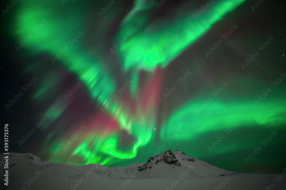 Vibrant Icelandic northern lights over mountain peaks in winter. Aurora Borealis near Vik, Iceland. 