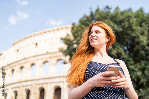 Photography Smiling female tourist with smartphone on sunny day near attraction