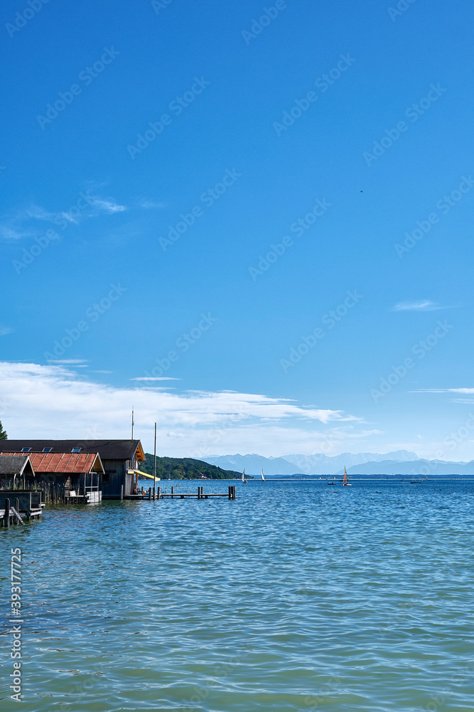 wooden houses on the sea at lake Starnberg with the alps in the background