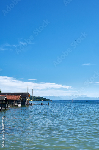 wooden houses on the sea at lake Starnberg with the alps in the background
