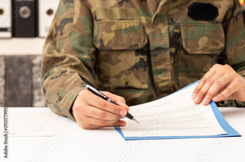 Fotografie Close up of executive military man hands signing contract on a desk at work