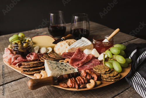 Close up of charcuterie board and glasses of wine on wooden table. photo