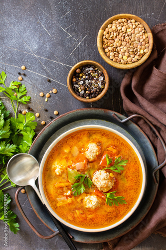 Tomato-lentil soup with meatballs and vegetables on a dark slate table top. Top view flat lay background. Copy space.