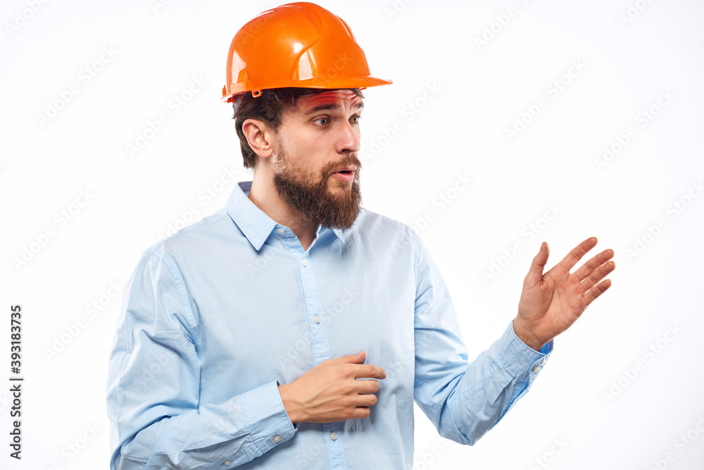 A man in an orange helmet shirt construction industry worked light background A man in an orange helmet shirt construction industry worked light background
