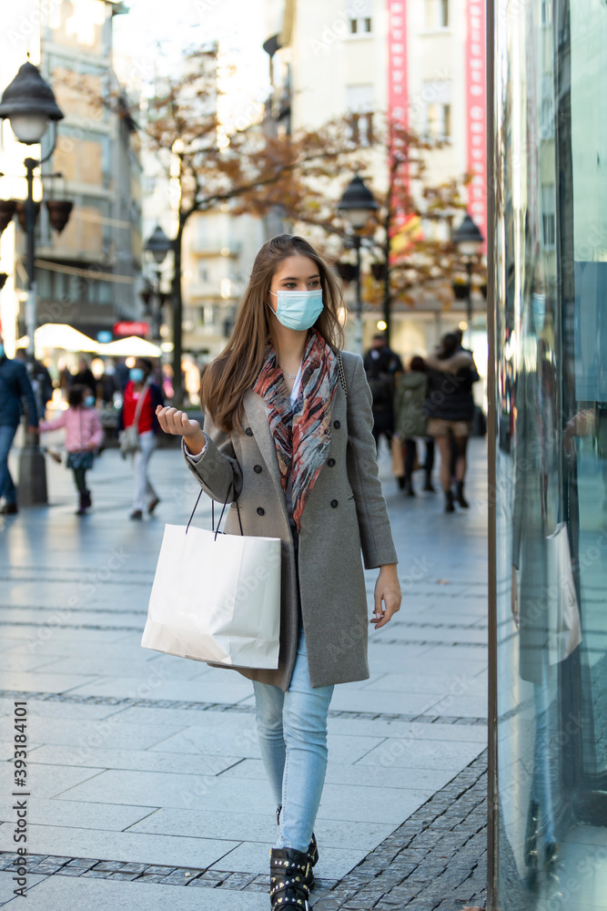 Young fashion woman wearing protective mask looking display window Young fashion woman wearing protective mask looking display window