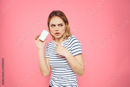 Woman with a business card in her hands a striped T-shirt pink background Copy Space advertising
