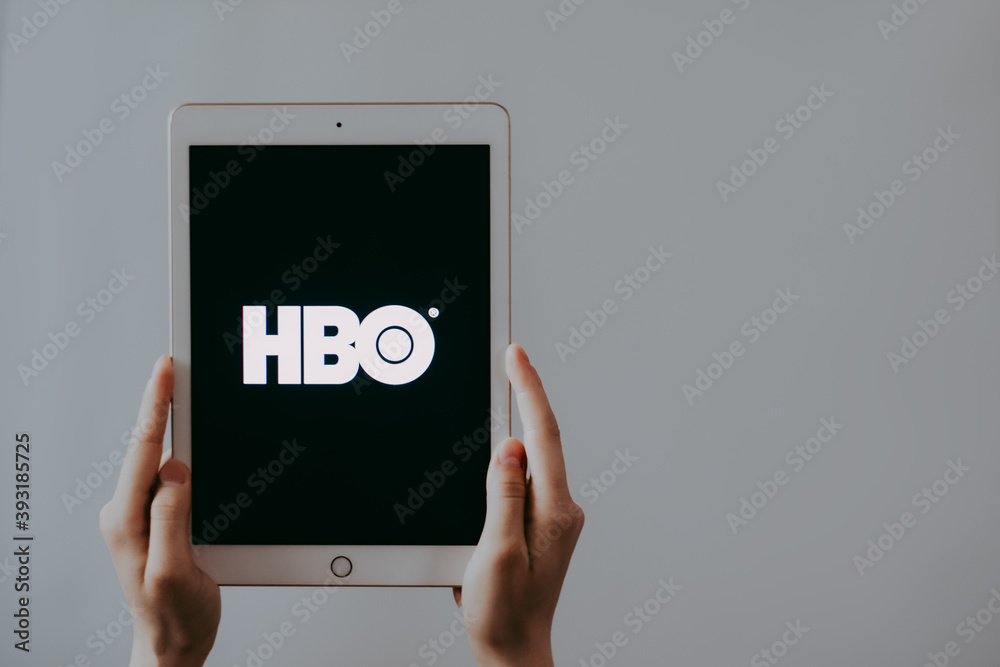 Stockfoto Home Box Office, hands holding iPad with HBO logo on the screen.  | Adobe Stock