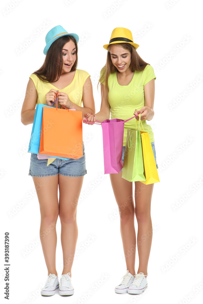 Young happy girlfriends in fashion clothing with shopping bags on white background Young happy girlfriends in fashion clothing with shopping bags on white background