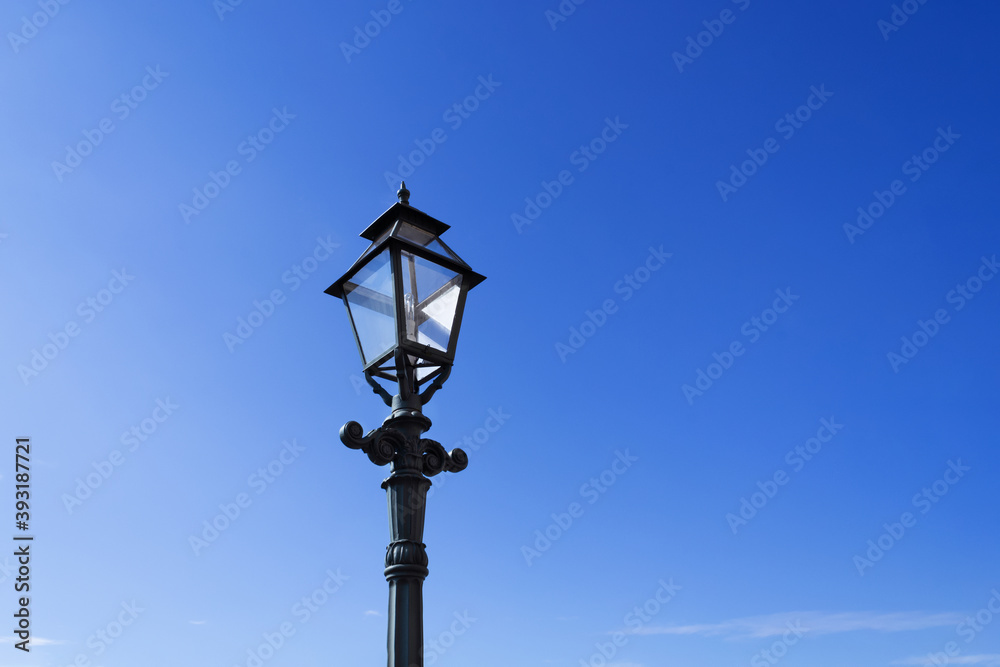 Retro street lamp on clear blue sky background.