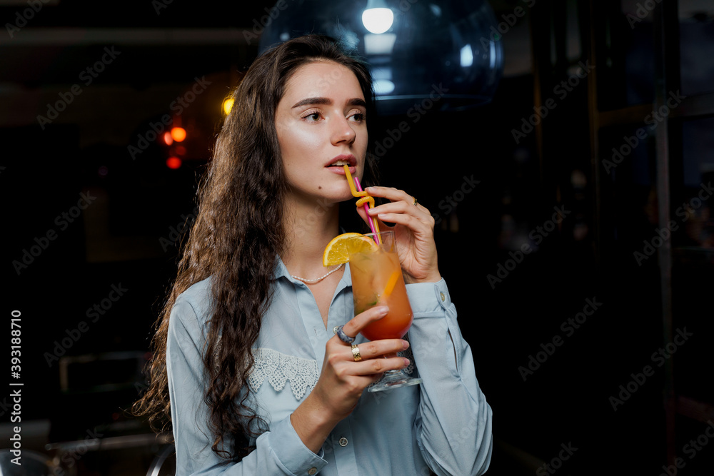 Girl with cocktail is drinking in night club before party. Advert for bar and night clubs. Citrus alcohol drink with orange juice Girl with cocktail is drinking in night club before party. Advert for bar and night clubs. Citrus alcohol drink with orange juice